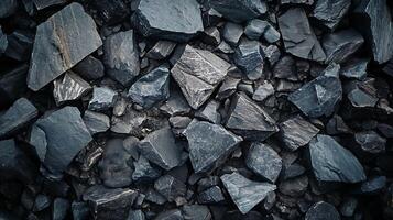 Abstract view of fractured dark stone fragments scattered under dim light, showcasing textures and shapes in a minimalist geological pattern. photo