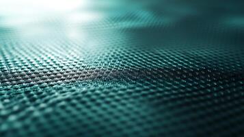 A textured surface with a patterned design, featuring a weave-like structure with a gradient teal color scheme and shallow depth of field. photo