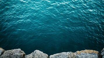 Turquoise waters gently lap against rugged, textured rock formations, creating a serene coastal scene. photo