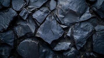 A dramatic texture photograph showing dark volcanic rocks glistening in the light. The rocks are angular and tightly packed, a striking pattern. photo