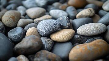 Pile of assorted smooth rocks in varying shades of grey and brown create a naturally textured surface. photo