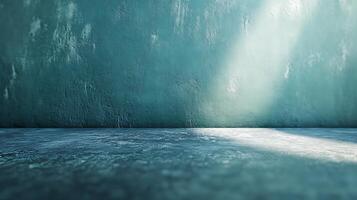 Light illuminates a textured blue wall and floor creating a minimalist, moody atmosphere. The contrast of light and shadow adds depth. photo