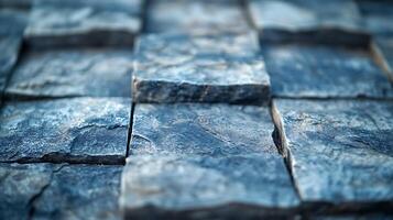 Close-up of a textured wall of stone square tiles. The tiles are different sizes and textures, and they are varying tones of grey and blue. photo