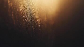 Textured surface with a golden sheen. A rustic wall with texture fades into the darkness, highlighting the granular structure and golden light. photo