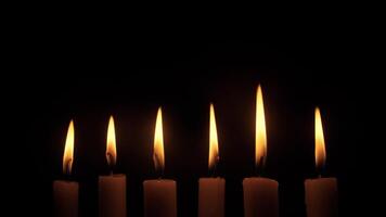 A serene and tranquil arrangement of six flickering candle flames illuminating a dark and moody backdrop video