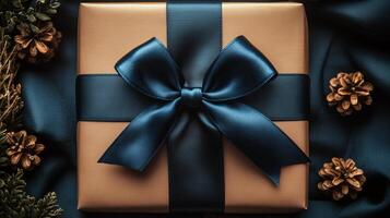 Gift box with blue ribbon and pine cones on a dark blue satin photo