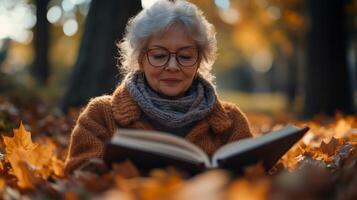 An older woman reading a book in the fall photo