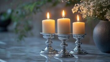 Three candles sit on a table next to a vase photo