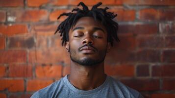 A man with dreadlocks is sleeping against a brick wall photo
