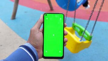 Using a smartphone with a green screen in a vibrant playground setting video
