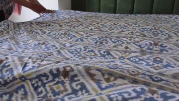 Making a cozy bed with patterned blanket and green headboard video