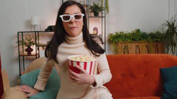 Woman sitting on couch eating popcorn and watching interesting TV serial, sport game online at home video