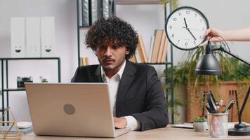 Indian businessman with anxiety checking time on clock, running late to work being in delay deadline video