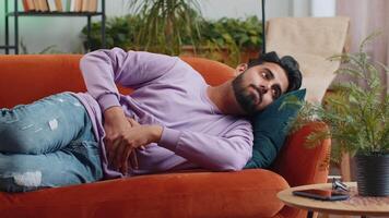 Indian man lying on sofa feeling sudden strong abdominal stomach ache, gastritis problem, diarrhea video