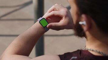 Athletic man looking at left hand with smartwatch chroma key, touching interacts with green screen video