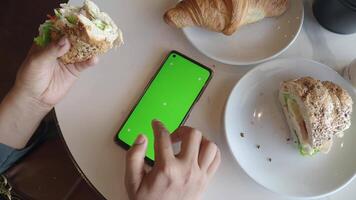 Enjoying a healthy breakfast with a smartphone at a cafe table video