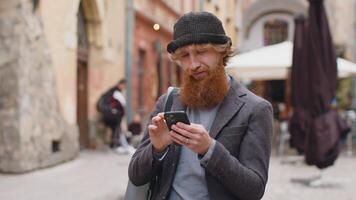 Young man use smartphone typing text messages browsing internet finishing work looking at camera video