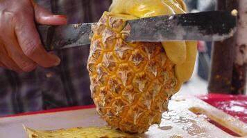Expertly slicing a fresh pineapple at a busy market stall video