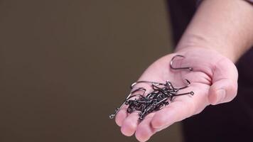 Fisherman holding many sharp fishing hooks in hand video