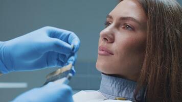 A patient smiles with confidence as a dentist examines her teeth using dental tools. The modern clinic emphasizes advanced healthcare techniques for optimal dental care. video