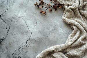Cozy knitwear and dried branch creating a warm autumnal atmosphere on marble background photo
