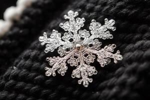 Close up macro photograph of snowflake resting on black woolen fabric photo