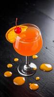 A cocktail with orange juice and a cherry on top photo