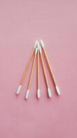 Three thin cotton swabs on pink background top view from above photo