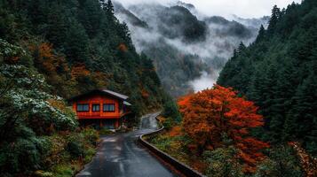 Scenic Autumn Road Winding Through Misty Mountain Forest with Cozy Wooden House photo