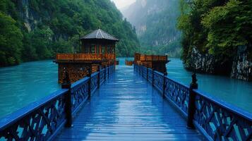 Serene Blue Wooden Bridge Leading to Gazebo on a Turquoise River in Lush Green Mountains under a Rainy Sky photo