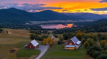 Stunning Sunset Over Rural Landscape with Two Red Barns near Lake and Mountains photo