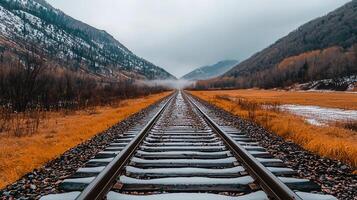 Scenic Winter Railroad Tracks Leading Through Snowy Mountains and Autumnal Fields A Journey Through Nature s Beauty photo
