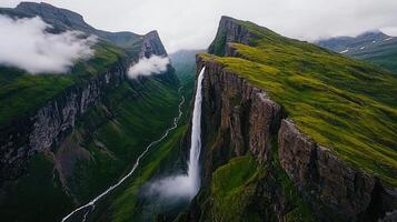 Majestic Waterfall Cascading Down a Steep Cliffside in a Lush Green Mountain Valley photo