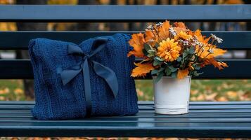 Cozy Autumn Scene Blue Knitted Throw Blanket and Autumn Flowers on Park Bench photo