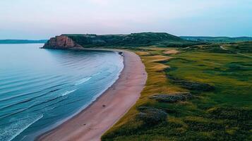 Serene Coastal Landscape Sandy Beach Meets Rolling Green Hills and Ocean Waves at Sunset photo