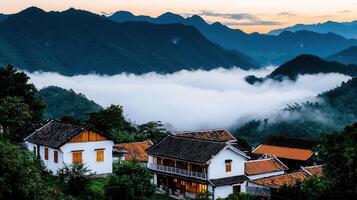 Scenic Asian Village Houses nestled in Mountains with Misty Clouds at Dawn photo