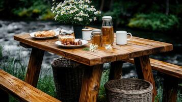 Rustic wooden picnic table outdoors by river with breakfast food and drinks Enjoy a relaxing morning meal in nature photo
