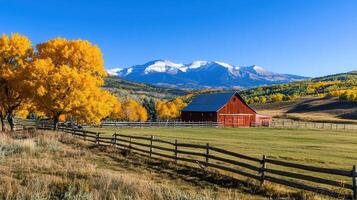 Scenic Autumn Landscape Red Barn in a Mountain Valley with Golden Aspen Trees and Wooden Fence photo