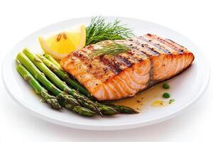 Grilled salmon fillet served with asparagus and lemon wedge on a white plate photo