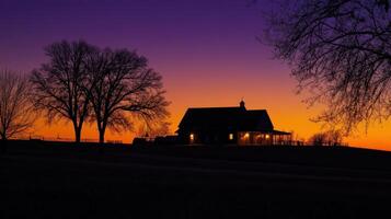 A serene silhouette of a farmhouse against a vibrant sunset sky photo