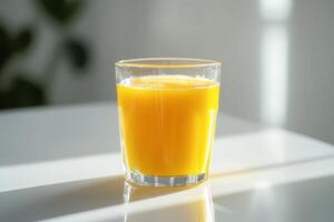 A glass of bright orange juice on a table with soft lighting. photo