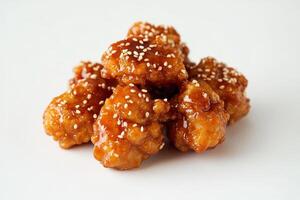 A pile of crispy chicken pieces coated in a sweet sauce and sprinkled with sesame seeds. photo