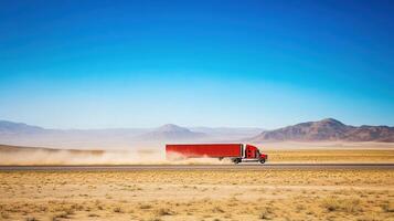 A red truck driving through a vast desert landscape under a clear blue sky. photo