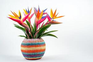 A vibrant arrangement of tropical flowers in a colorful woven pot photo
