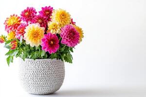 A vibrant bouquet of colorful flowers in a textured pot against a plain background photo