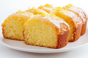 A close-up of sliced lemon cake with a glossy glaze and lemon zest on top photo