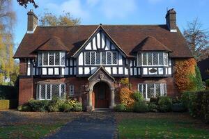 A charming Tudor-style house with a landscaped garden and autumn foliage photo