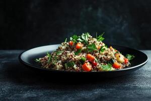 A vibrant quinoa salad garnished with vegetables and herbs on a dark background photo