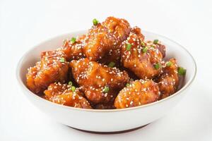 A bowl of crispy, glazed chicken pieces garnished with sesame seeds and green onions. photo