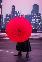 Mysterious Clown Performer with Red Umbrella in Urban Nightscape. photo